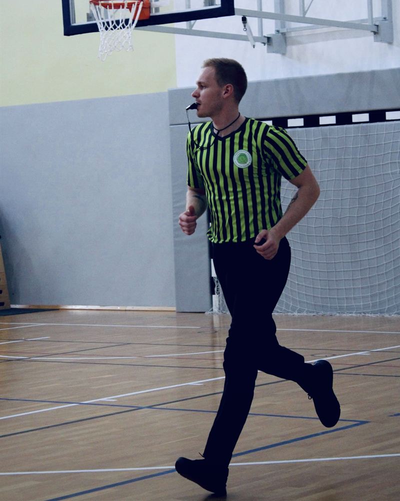 Polyák Adrián játékvezetőként fut a kosárlabdapályán, sípszóval a szájában